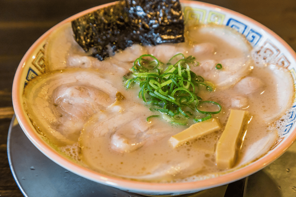 A bowl of Hakata tonkotsu ramen with layered chashu pork, nori and spring onions