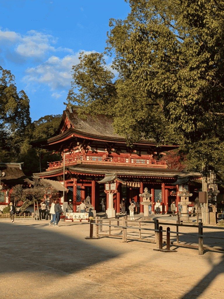 The vermilion two-storey romon gate of Dazaifu Tenmangu shrine in golden afternoon light