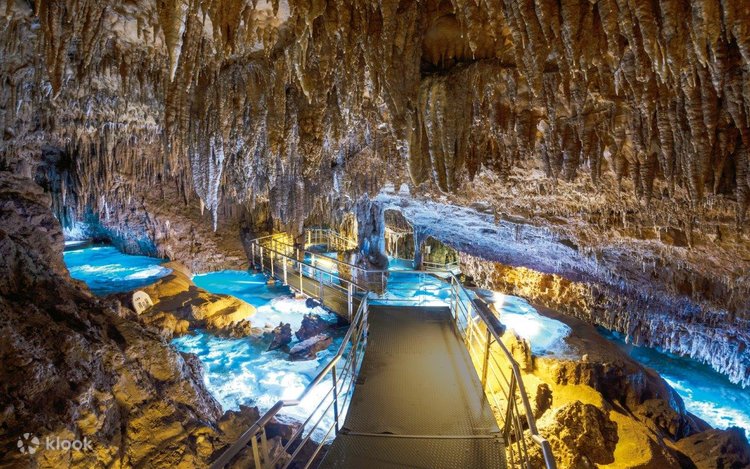Illuminated limestone stalactites and an underground stream inside Gyokusendo Cave