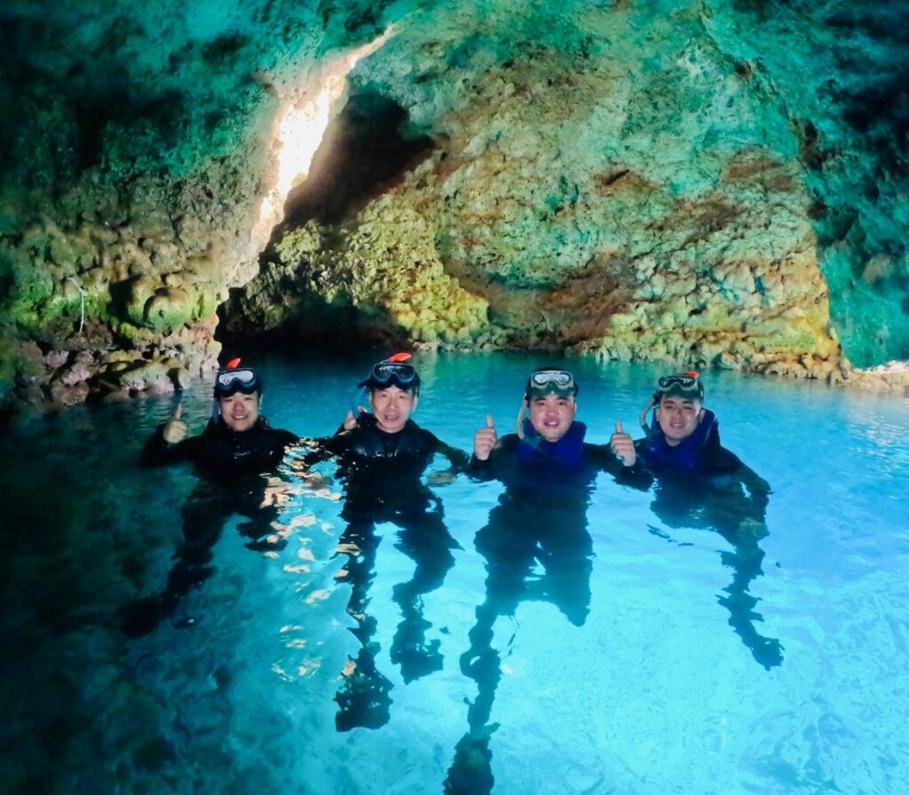 Snorkellers in the glowing blue water inside Cape Maeda's Blue Cave