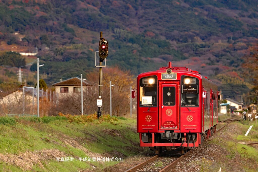 The red Coto Coto sightseeing train running through the Fukuoka countryside in autumn