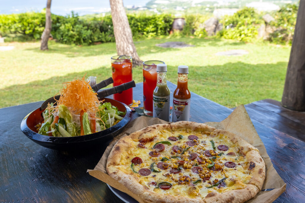 A wood-fired pizza and salad on an outdoor table with a garden view at Pizza in the Sky