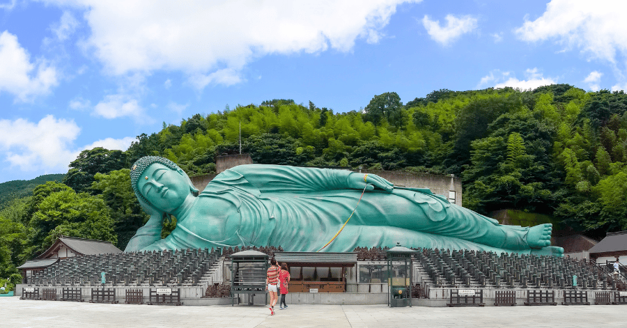 The giant bronze reclining Buddha at Nanzoin temple, with visitors dwarfed at its base