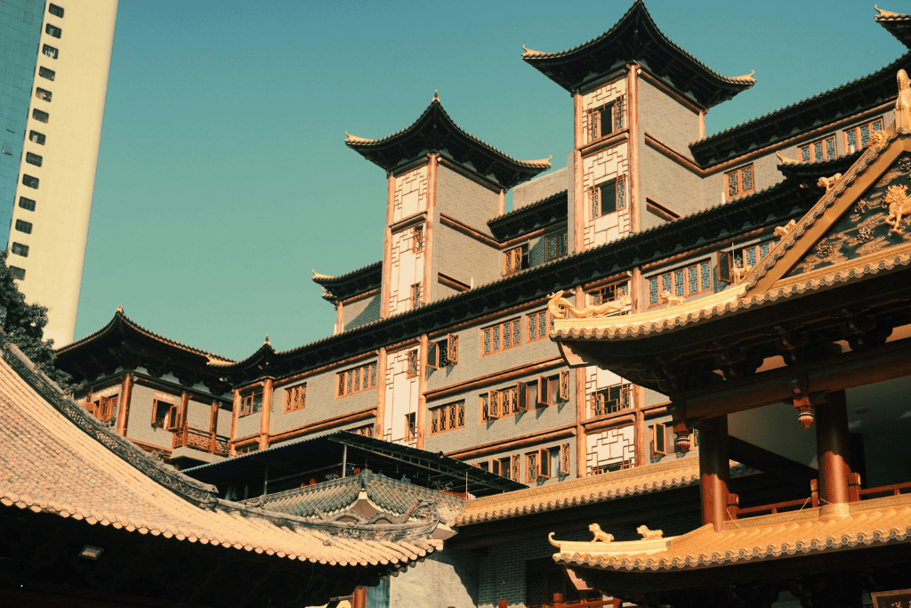 Ornate Lingnan-style building with tiered pavilion roofs beside a modern tower in Guangzhou