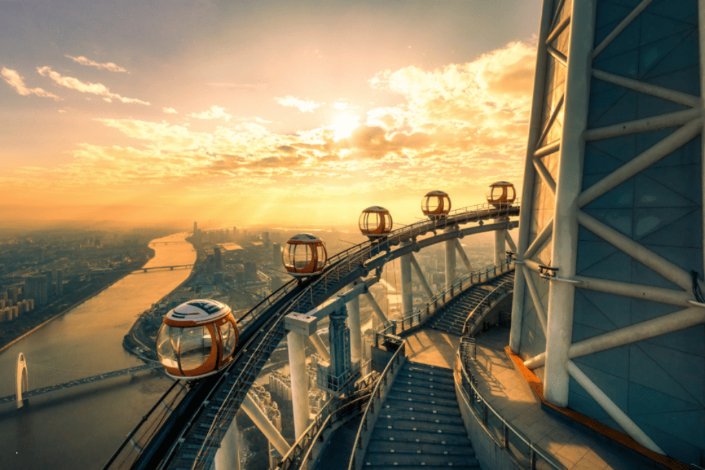 Glass Bubble Tram pods circling the top of Canton Tower above the Pearl River at sunset