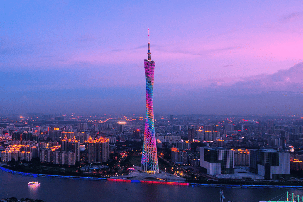 Canton Tower glowing in shifting colours at dusk above the Guangzhou skyline and Pearl River