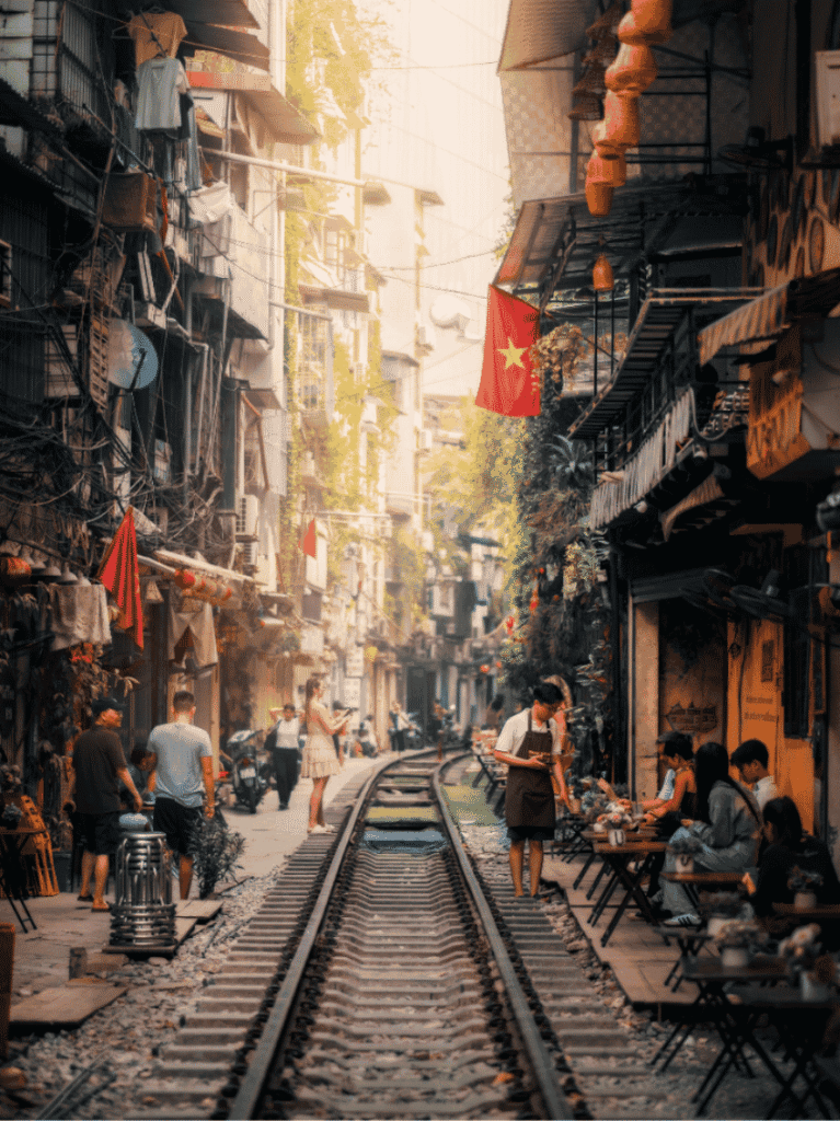 Railway track running between shophouses on Hanoi's Train Street, with cafe tables alongside