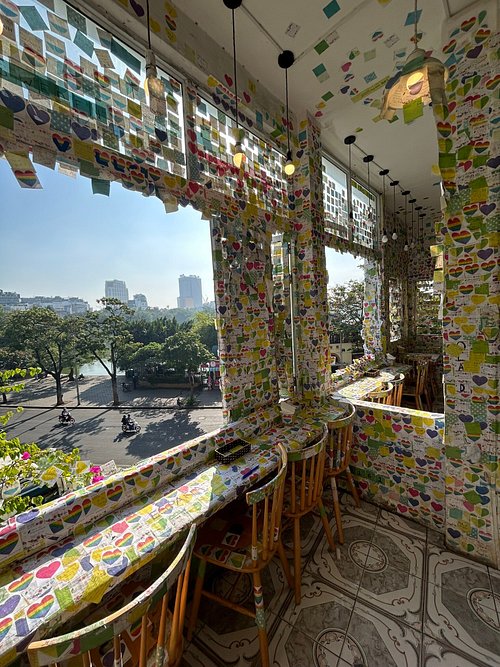 Cafe interior papered floor to ceiling in coloured sticky notes, with lake views through the windows