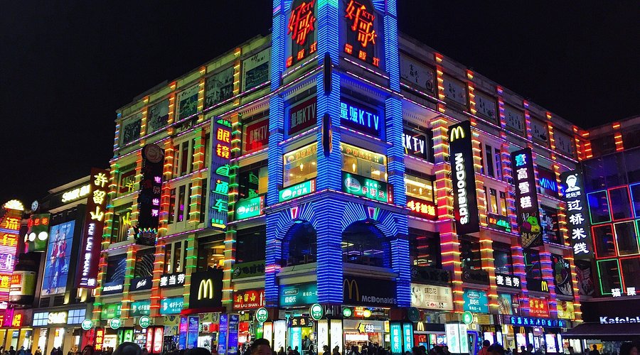 Neon-lit qilou arcade buildings lining Shangxiajiu Pedestrian Street at night in Guangzhou