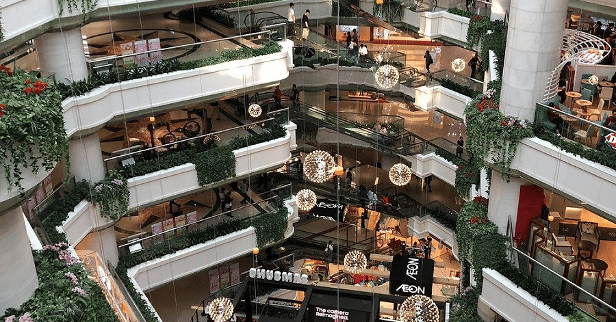 Planted balconies and hanging light globes across the levels of a modern mall in Tianhe District