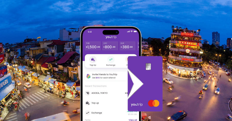YouTrip card and app showing multiple currency balances above a Hanoi street at dusk