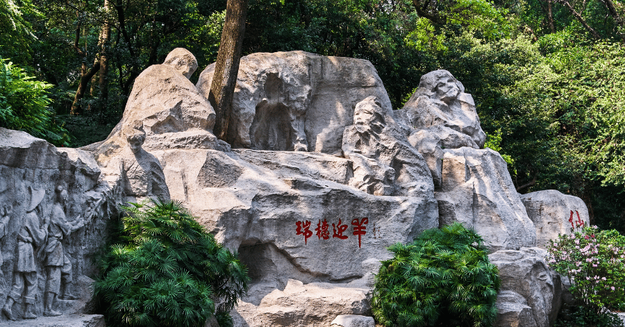 A rugged stone sculpture with engraved red characters framed by greenery in Yuexiu Park
