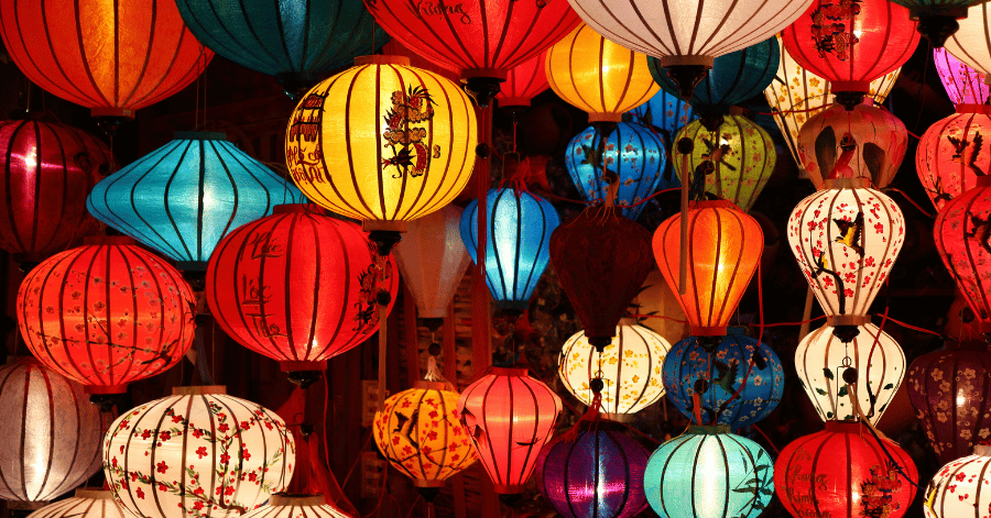 Densely hung Vietnamese silk lanterns in red, blue, pink and yellow, lit from within