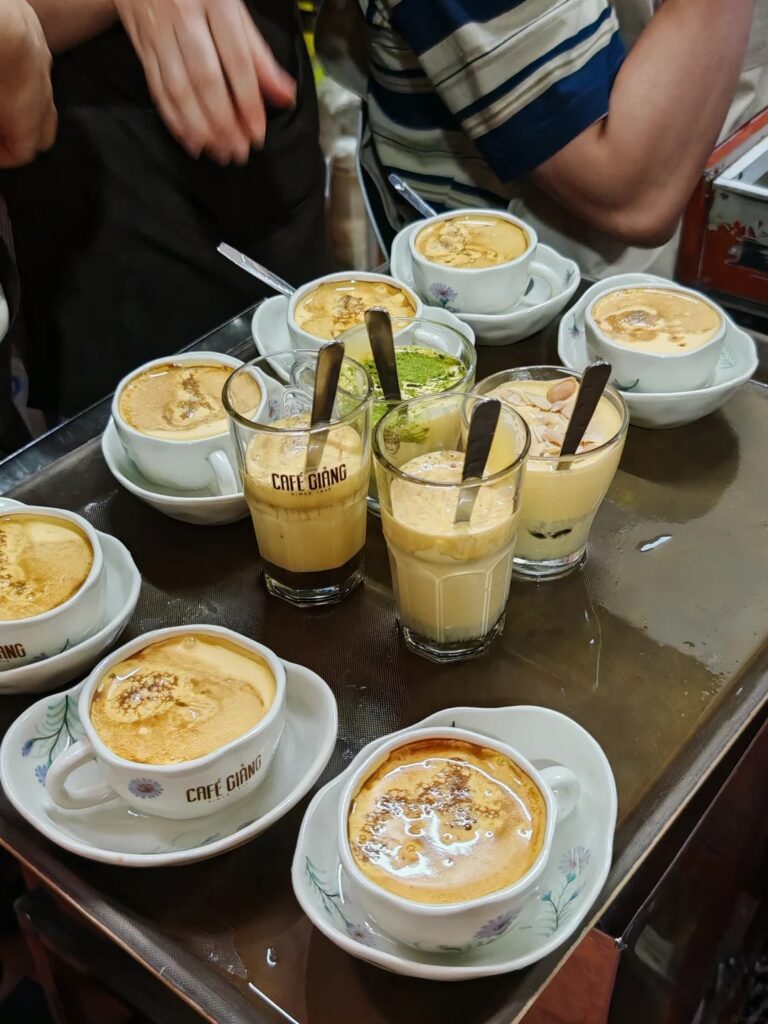 Tray of egg coffees in branded Cafe Giang cups, hot and iced, with matcha and salted variants