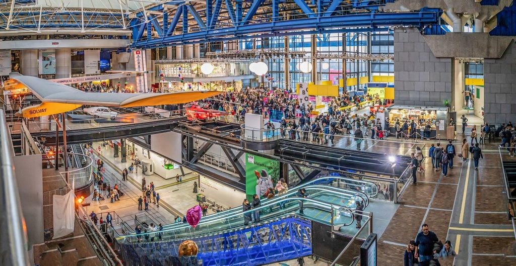 Families and visitors exploring exhibits and escalators inside the Cité des Sciences et de l'Industrie