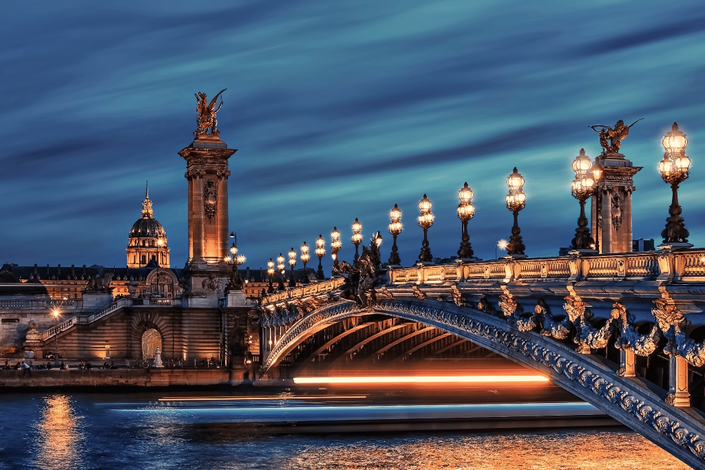 Pont Alexandre III bridge lit up at night over the Seine with Les Invalides in the background