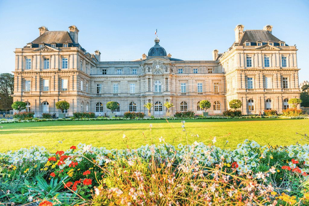 The Luxembourg Palace facade behind a lawn and flower beds in the Jardin du Luxembourg