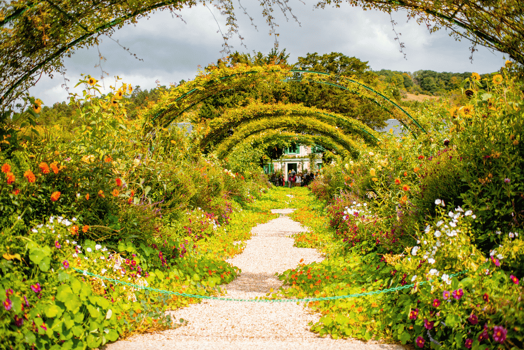 A flower-lined path leading under rose arches toward Monet's house at Giverny