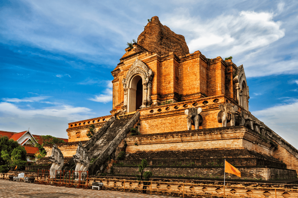 The large ruined brick chedi of Wat Chedi Luang with elephant carvings under a blue sky
