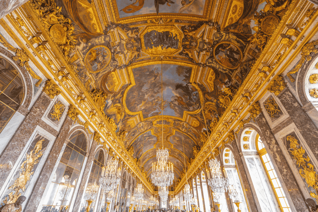 The gilded, mirror-lined Hall of Mirrors at the Palace of Versailles with painted ceiling and chandeliers