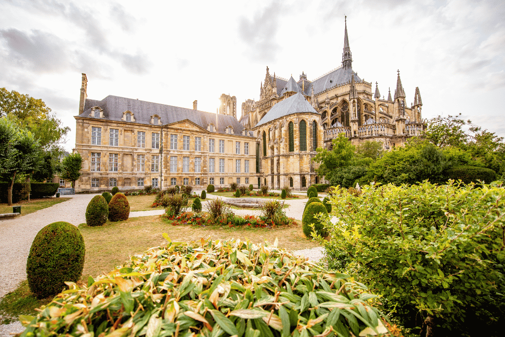 Reims Cathedral's Gothic spires rising behind manicured gardens