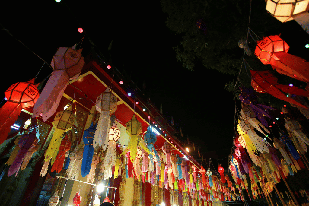 Rows of colourful hanging Lanna paper lanterns lighting up a temple at night in Chiang Mai