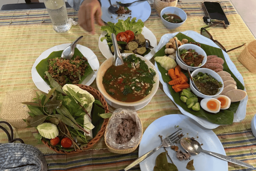 A banana-leaf spread of Northern Thai dishes: larb, chilli-tomato dip, sausage, boiled egg and vegetables