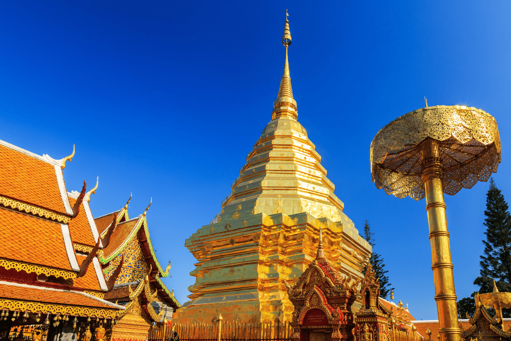 The golden chedi and ornate umbrella of Wat Phra That Doi Suthep against a blue sky