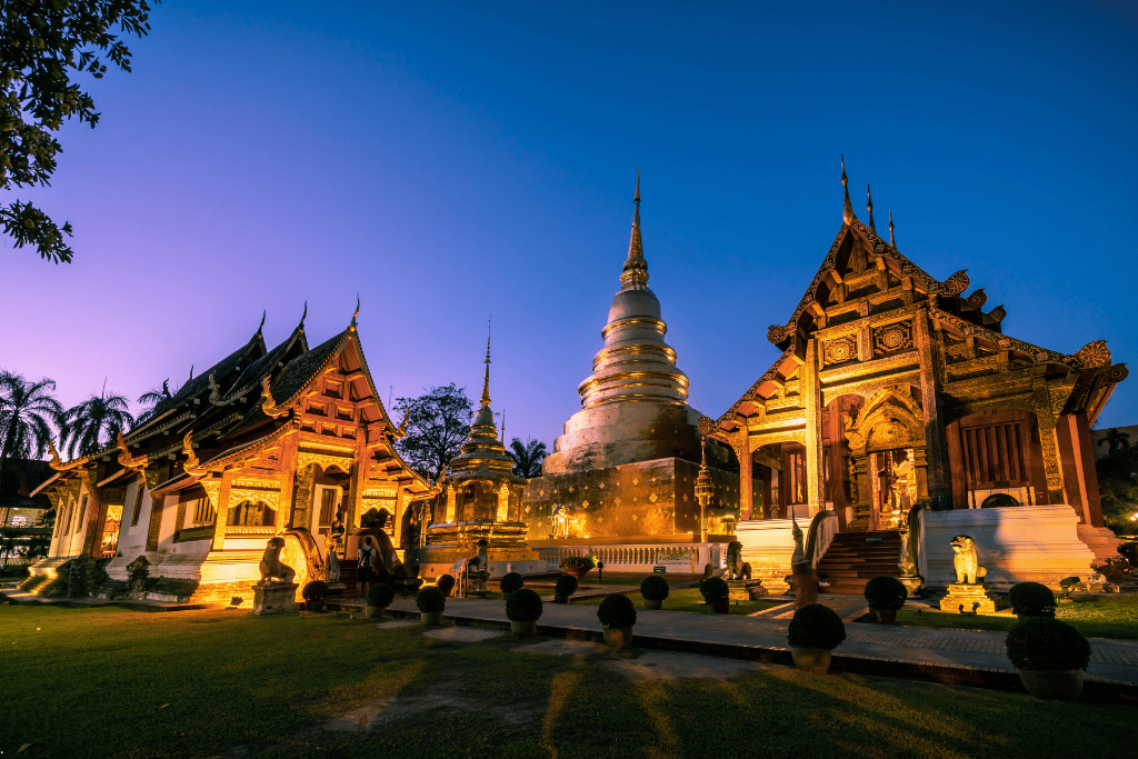 The golden temple halls and silver chedi of Wat Phra Singh lit up at dusk