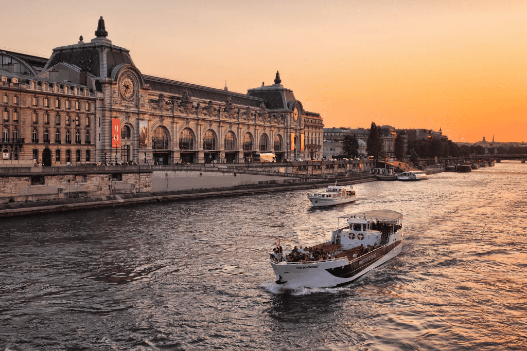 A Seine river cruise boat passing the Musée d'Orsay building at sunset