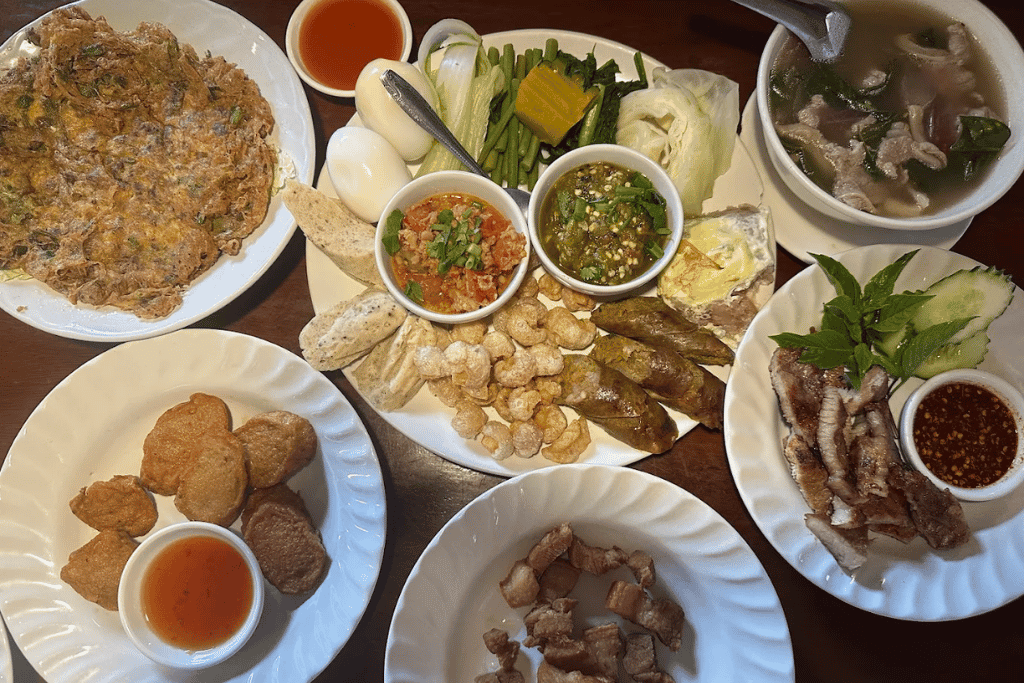 A spread of Northern Thai dishes including a herb omelette, chilli dips, pork rinds and soup