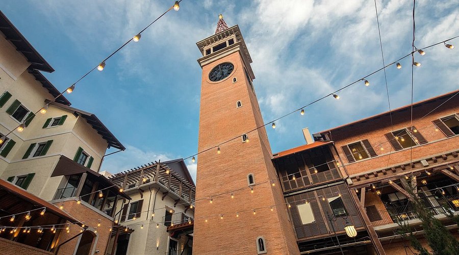 The brick clock tower and string lights of One Nimman against a blue sky in Nimman district
