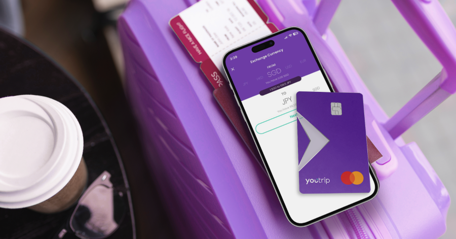 A purple YouTrip Mastercard and the YouTrip app showing an SGD to JPY exchange, on a suitcase