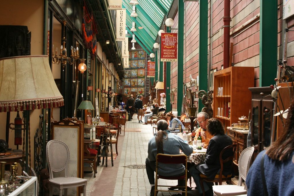 Antique stalls and shoppers inside a covered passage at the Marché aux Puces de Saint-Ouen flea market