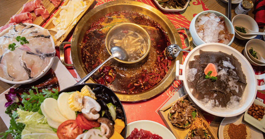 An overhead spread of Chongqing mala hotpot and side dishes