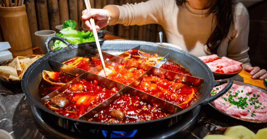 A diner cooking meat in a bubbling Chongqing mala hotpot
