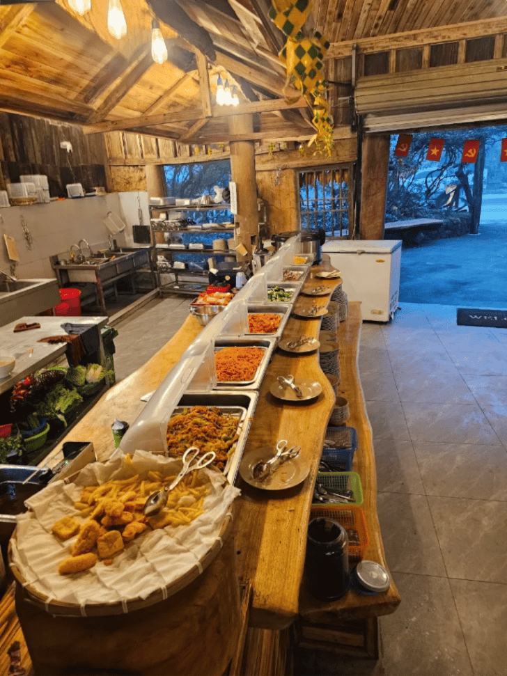 Trays of buffet food along a live-edge wooden counter in a rustic timber restaurant