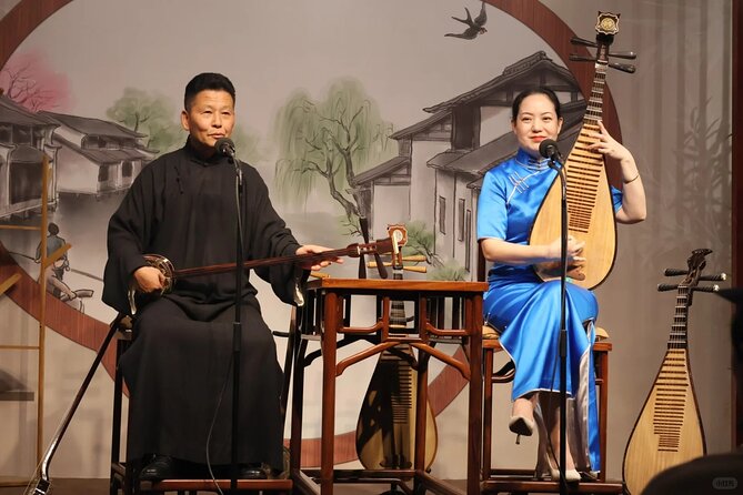 A man with a bowed instrument and a woman holding a pipa performing Suzhou Pingtan on stage