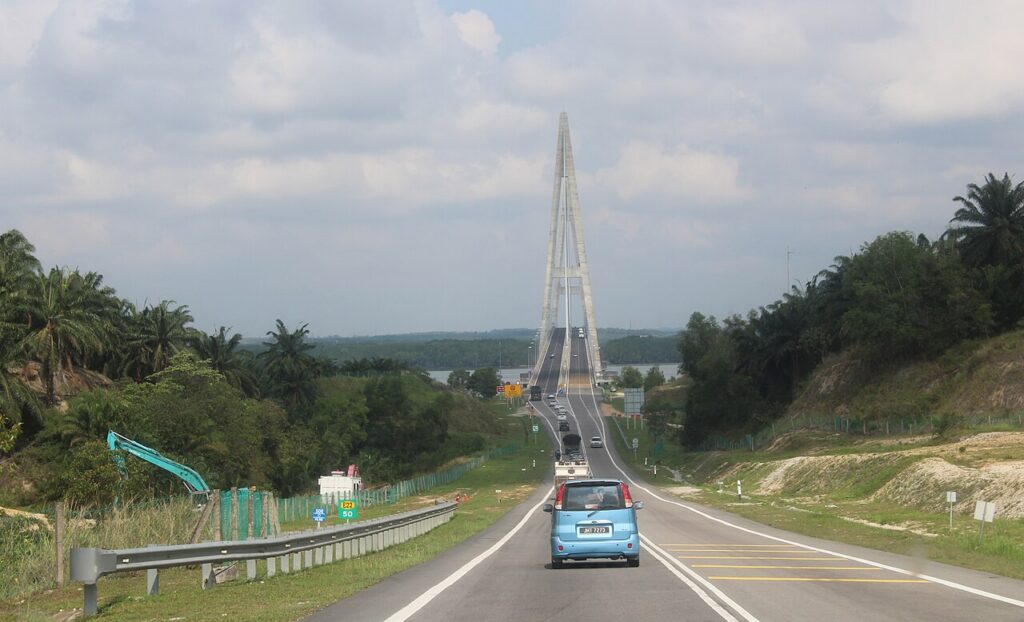 Cars approaching the cable-stayed Sungai Johor Bridge on the palm-lined Senai-Desaru Expressway