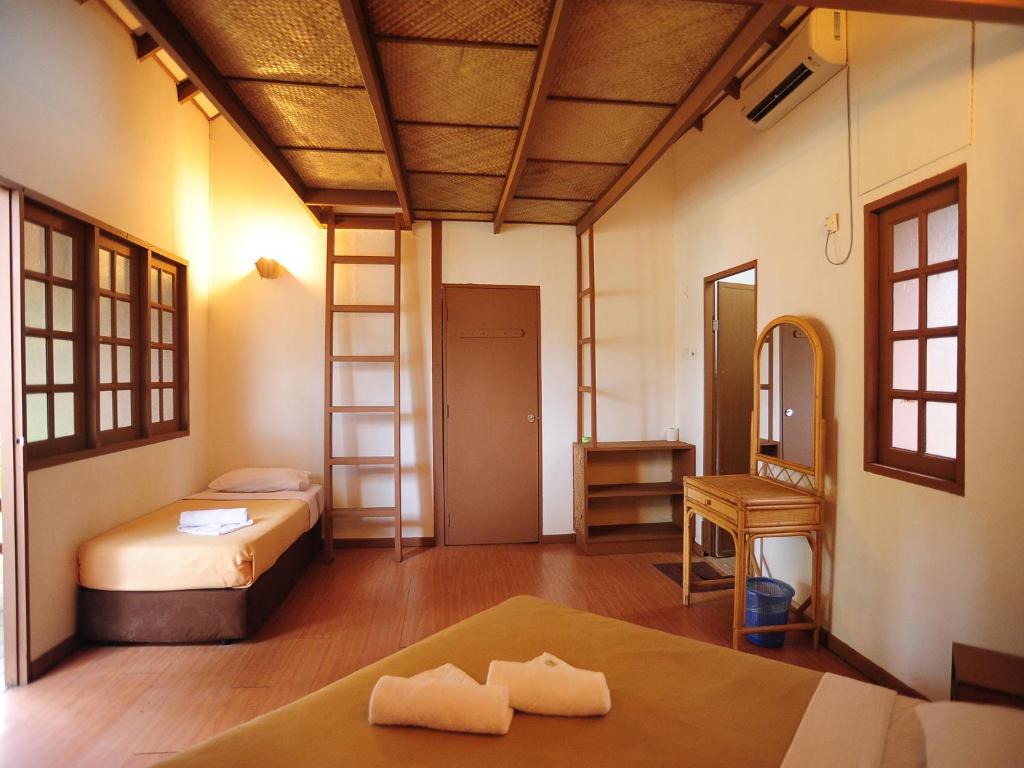 Interior of a simple twin-bed chalet room with wooden floor, woven ceiling and air-con