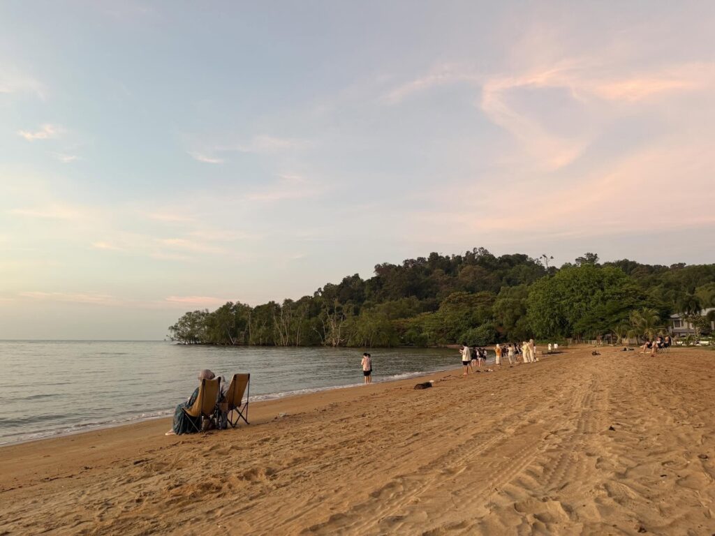 Quiet sandy beach at dusk with a forested headland, Pantai Cermin in Port Dickson