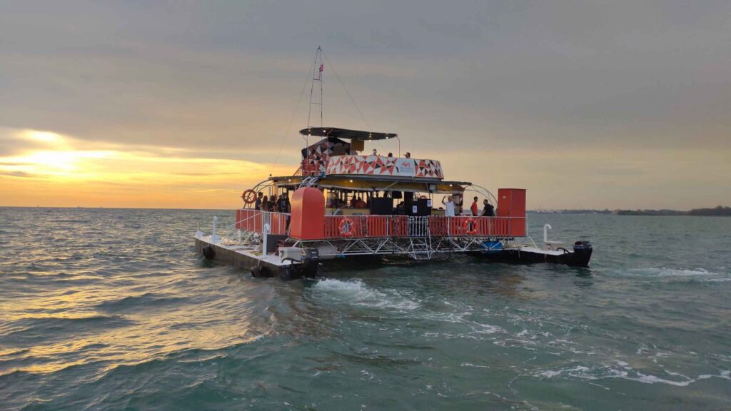 Red catamaran cruise boat carrying passengers on the sea at sunset