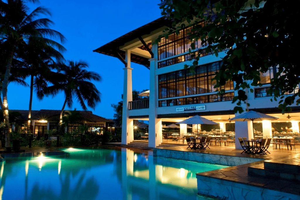 Resort building lit up at night reflected in a still poolside lagoon