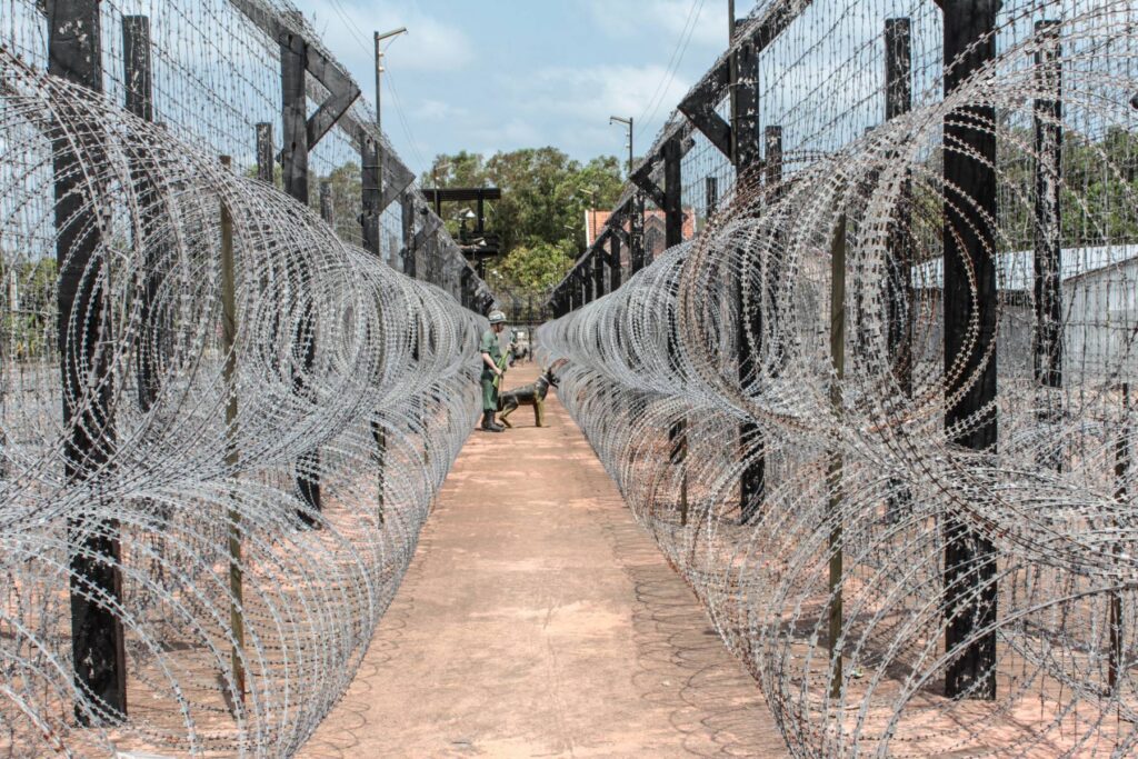 Barbed-wire fencing and a guard figure with a dog at Coconut Prison, Phu Quoc