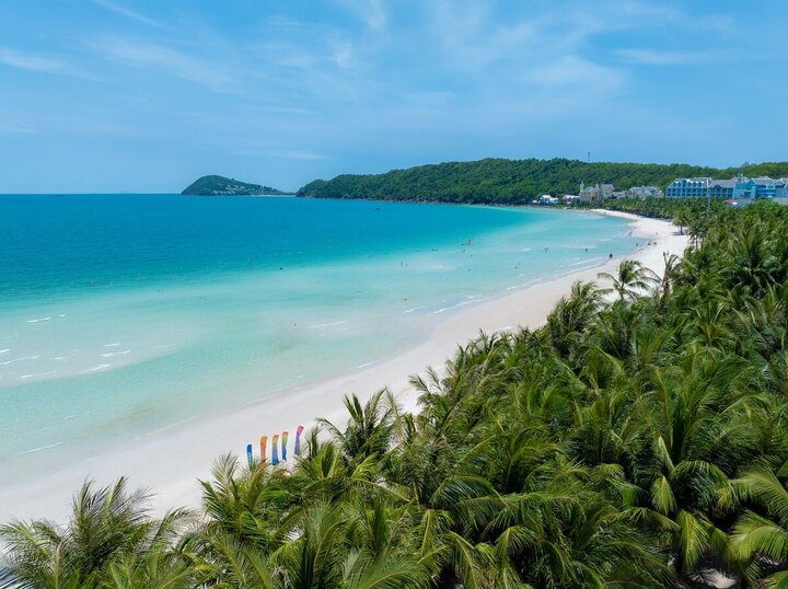 Aerial of Kem Beach's long white-sand bay, turquoise water and palm-backed resorts