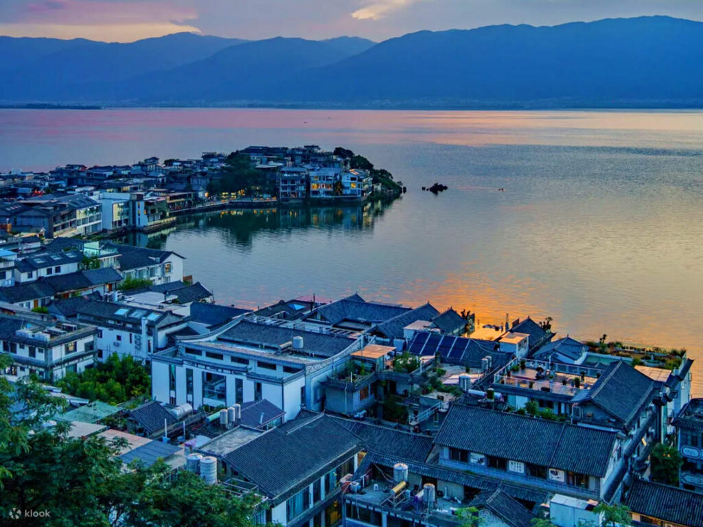 Grey-tiled rooftops of a Bai lakeside town beside Erhai Lake at sunset, Dali