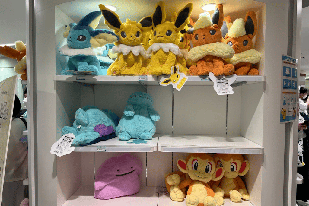 Store shelves displaying assorted Pokémon plush including Eevee evolutions, Ditto and Chimchar