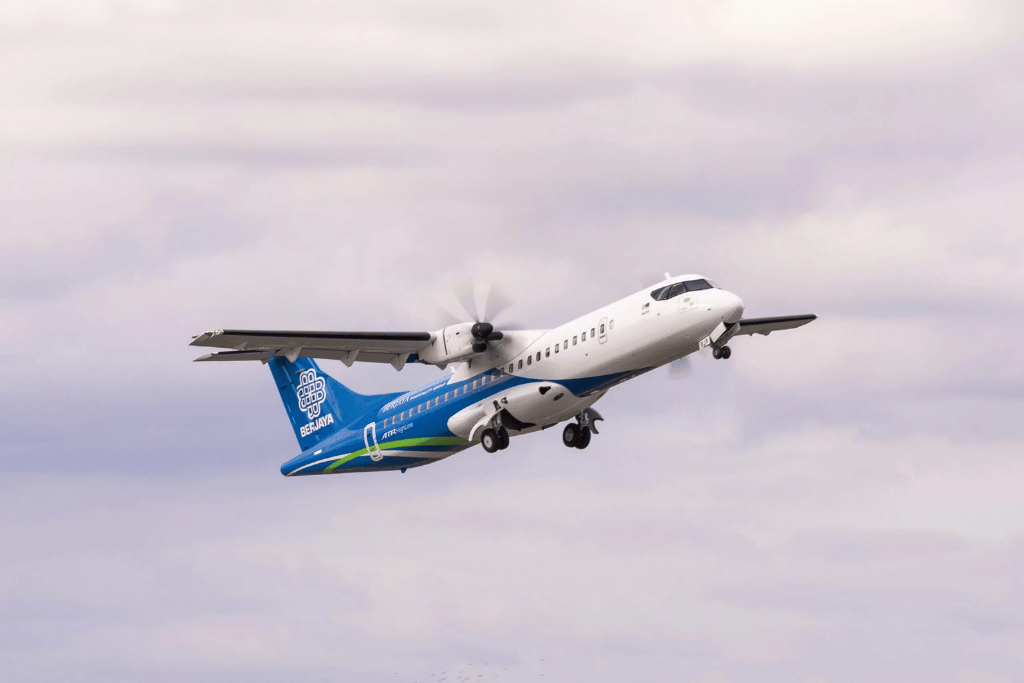 Berjaya Air turboprop plane taking off into a cloudy sky
