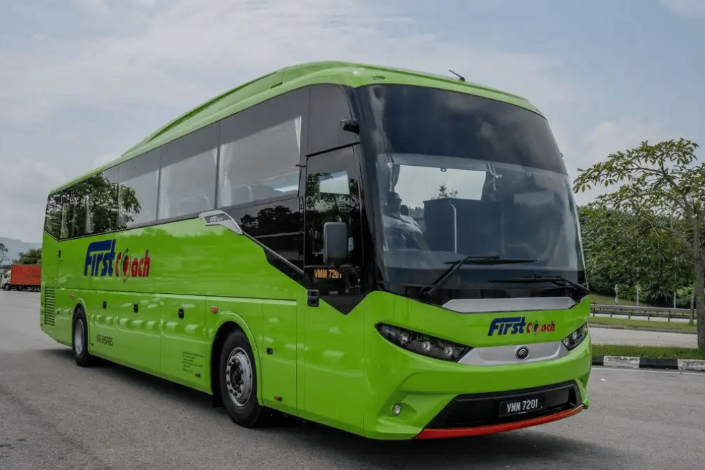 Green long-distance express coach parked at a depot