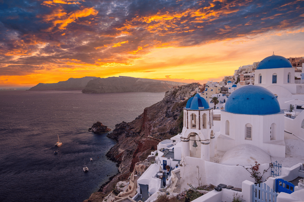 Oia's whitewashed cliffside houses and blue domes glowing under a fiery sunset